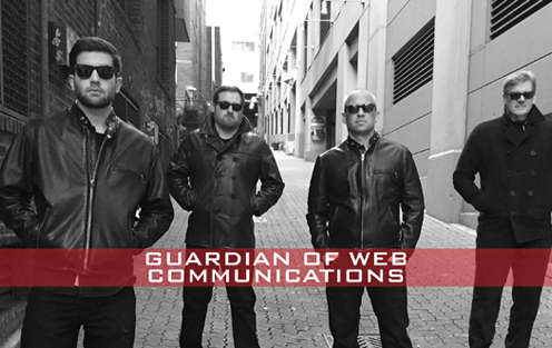 Four team members, Taggert, Justin, Josh, and Jeff stand in an alley wearing black jackets with shades on.